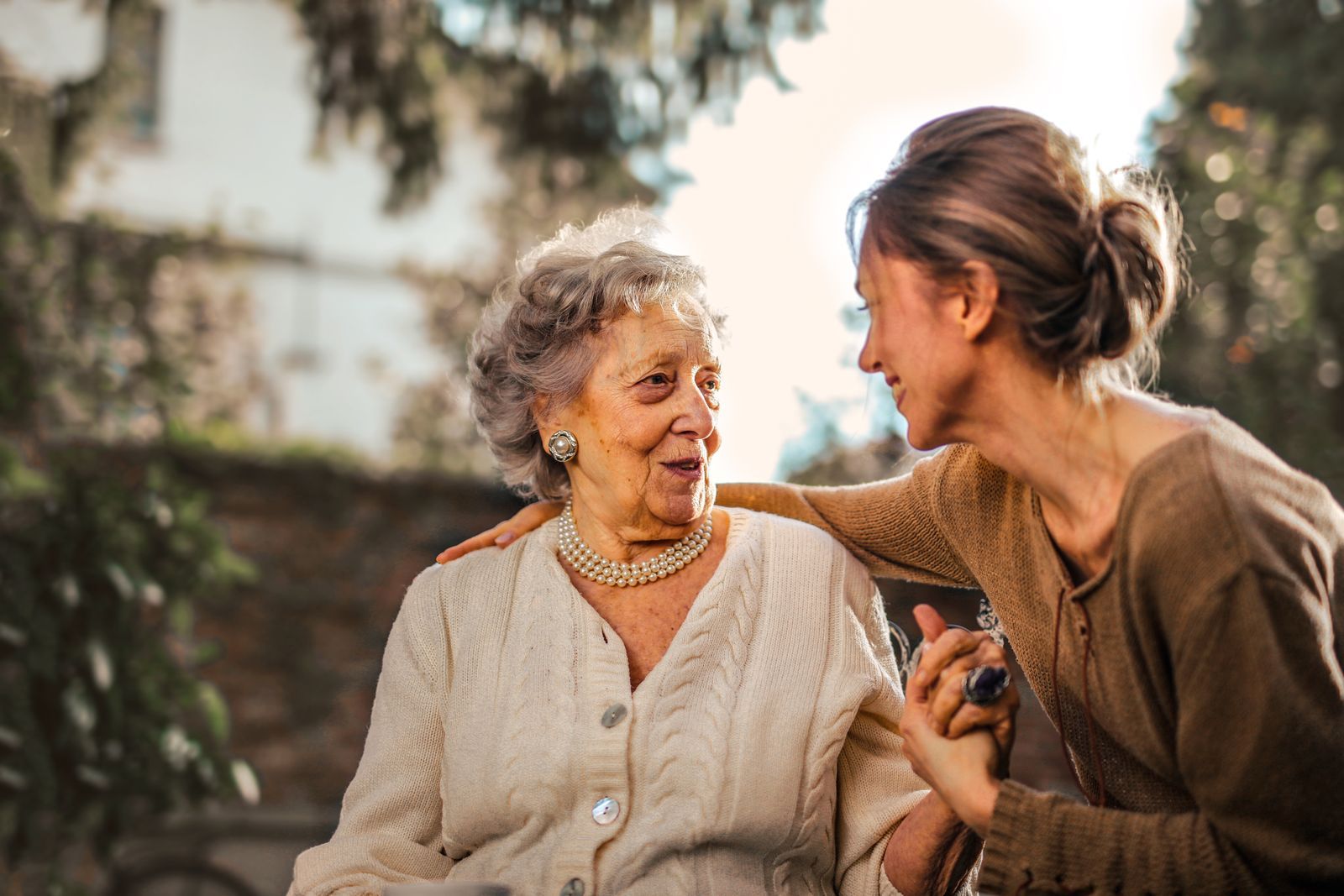 Adult daughter sharing a joyful moment with her senior mother in a garden